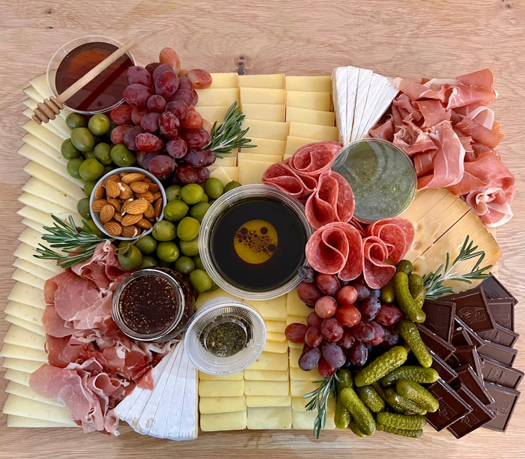 Assorted charcuterie board with meats, cheeses, fruits, and nuts on a wooden surface.