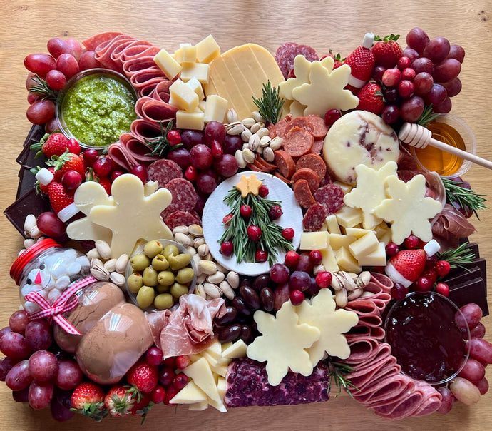 Assorted charcuterie board with meats, cheeses, fruits, and accompaniments on a wooden surface.